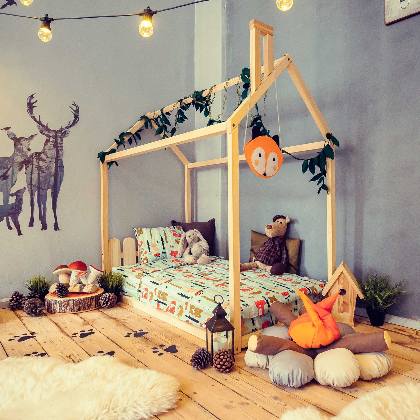 A children's room with a wooden bed and stuffed animals. The wooden bed in this children's room is a Kids' house-frame bed with a picket fence headboard, providing a low platform for toddlers and creating a cozy environment.