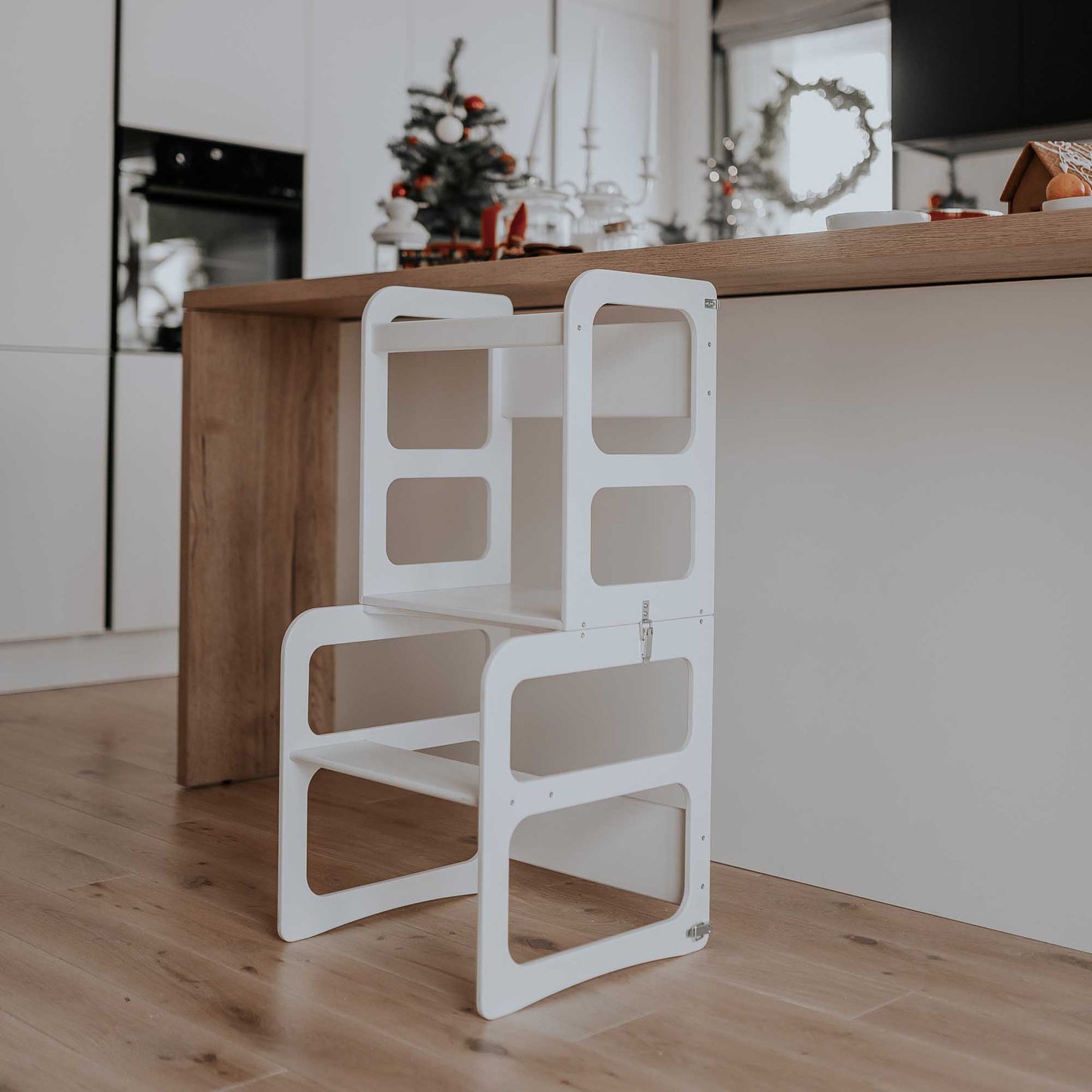 A white folding chair, also known as a Sweet Home From Wood 2-in-1 transformable kitchen tower - table and chair set, is placed in a kitchen.