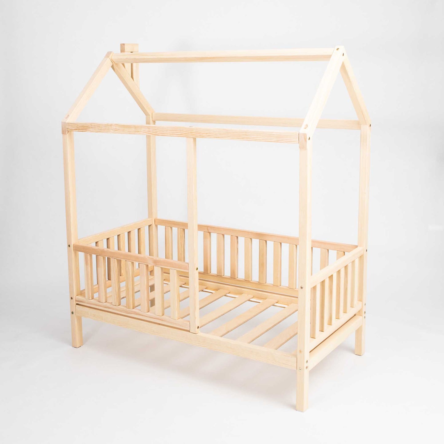 A Kids' house bed on legs with a fence, with a wooden frame and slats, elevated on legs.