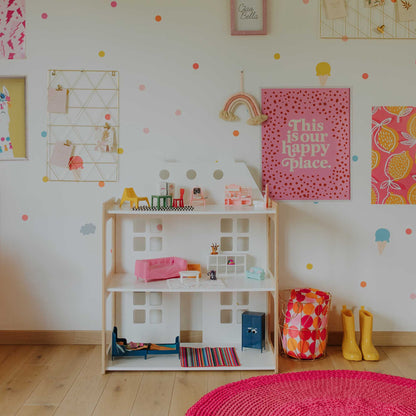 A girl's room with a Sweet Home From Wood 2-in-1 doll house and Montessori shelf and polka dots on the wall.