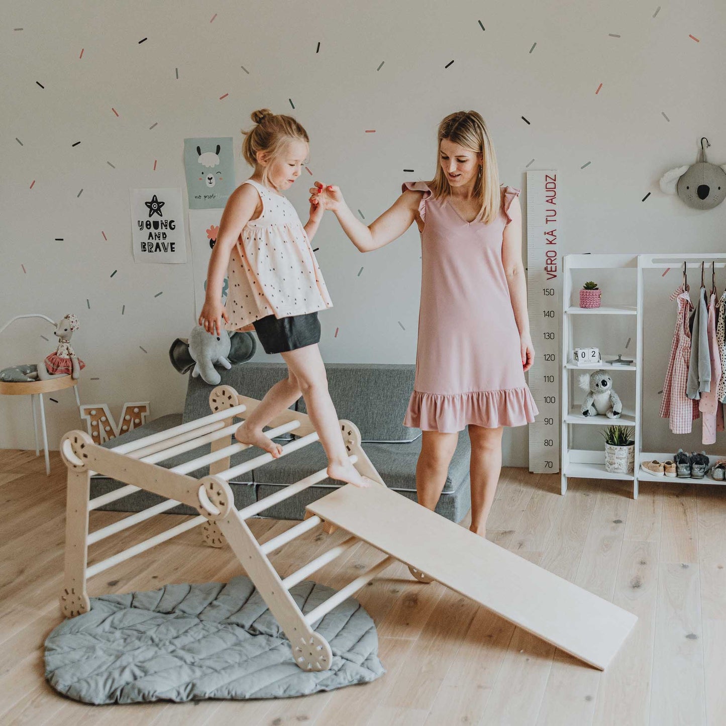 A woman and a little girl playing on a Sweet Home From Wood climbing triangle + Transformable climbing gym + ramp in a room.