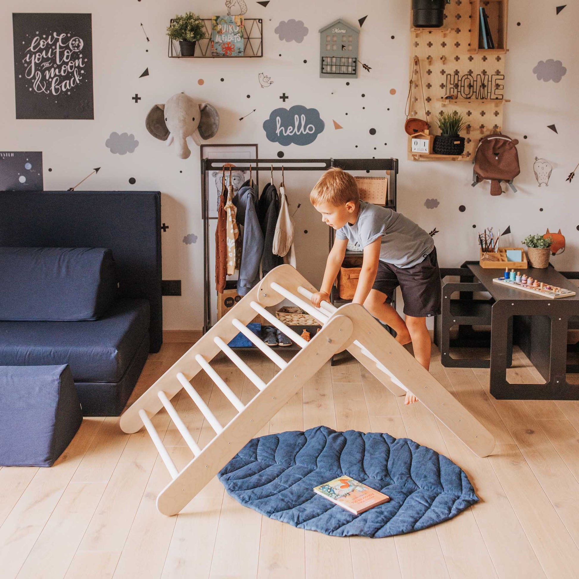 A boy is playing with a Foldable climbing triangle + Transformable climbing gym + a ramp in his room.