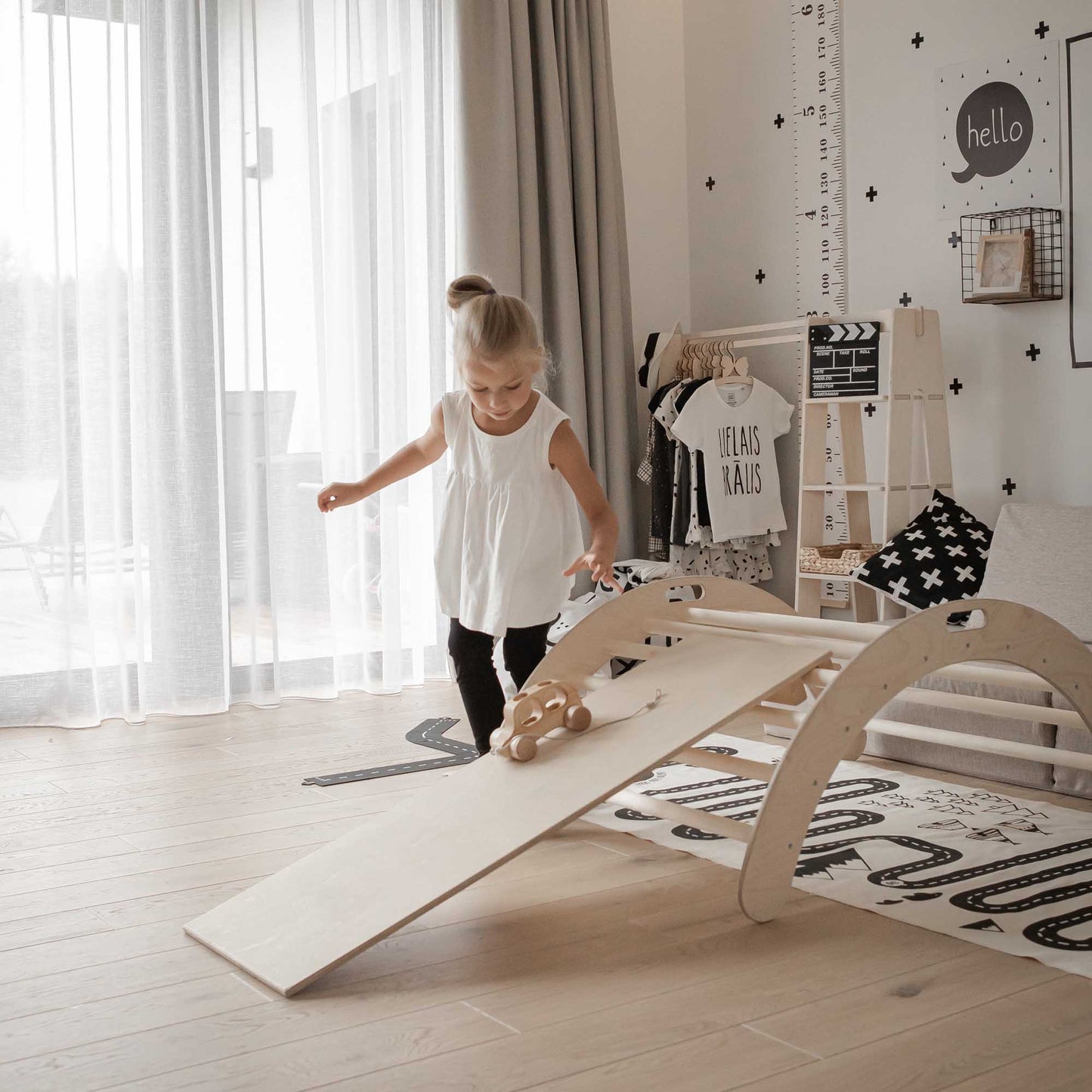 A little girl playing with a Sweet Home From Wood Climbing arch, Transformable climbing triangle, and ramp activity play set in her room.