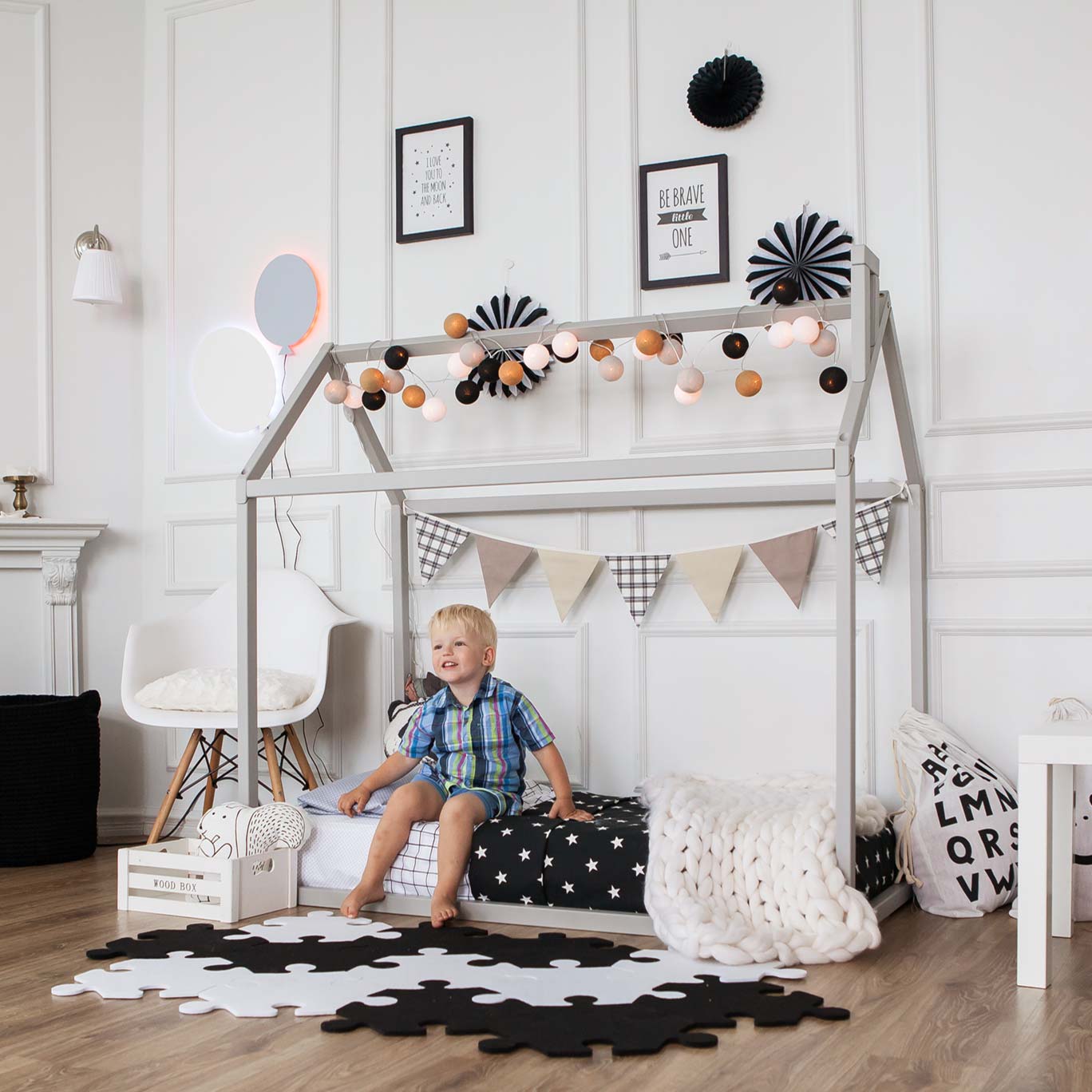 A child is sitting on a bed in a room with black and white decorations.