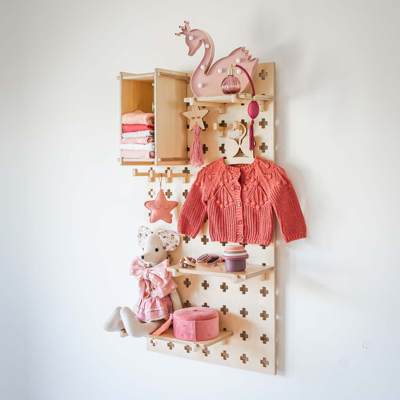 A wooden shelf with a pink swan hanging on it.