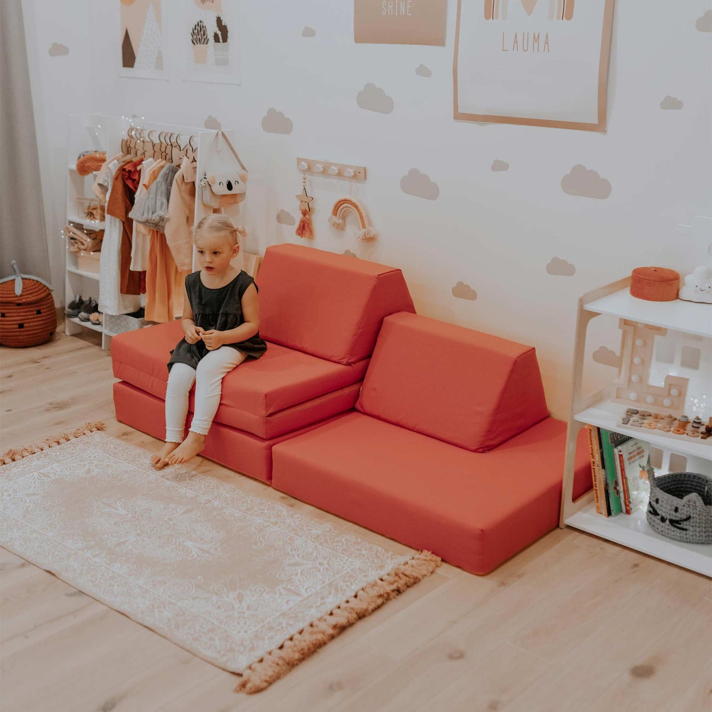 A child is sitting on a Sweet HOME from wood activity play couch set in a room.