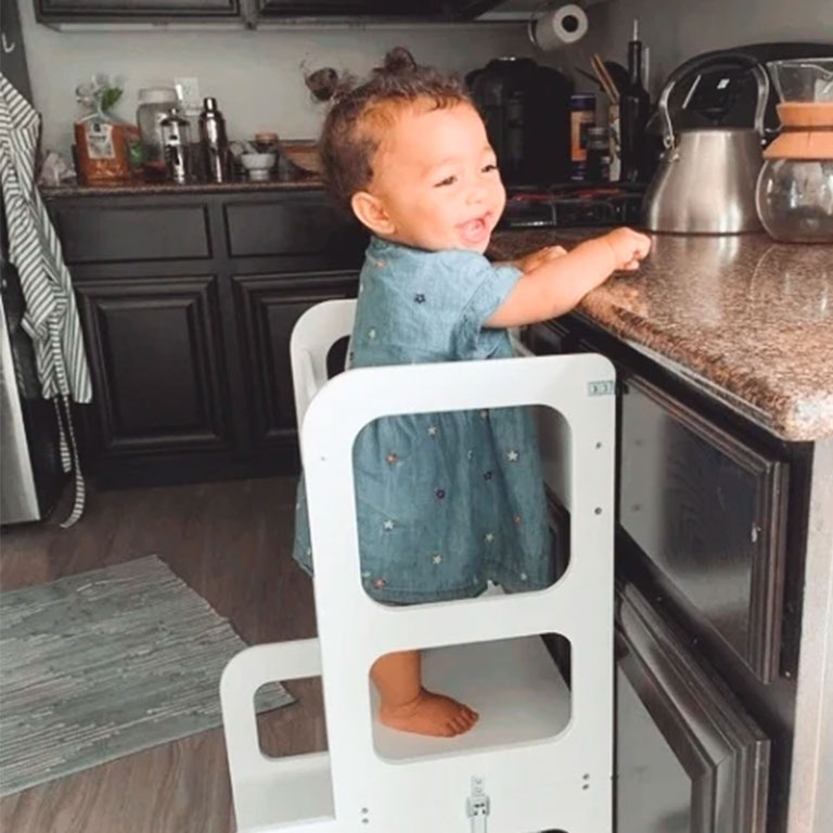 Customer photo of a baby girl laughing in a kitchen step stool.
