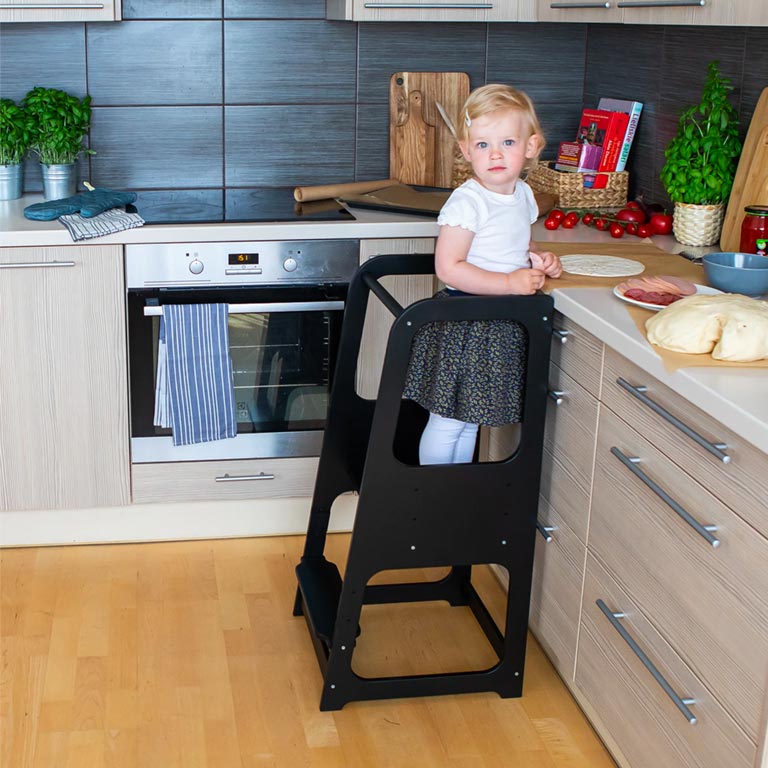 Customer photo of a baby girl standing in a kitchen tower.