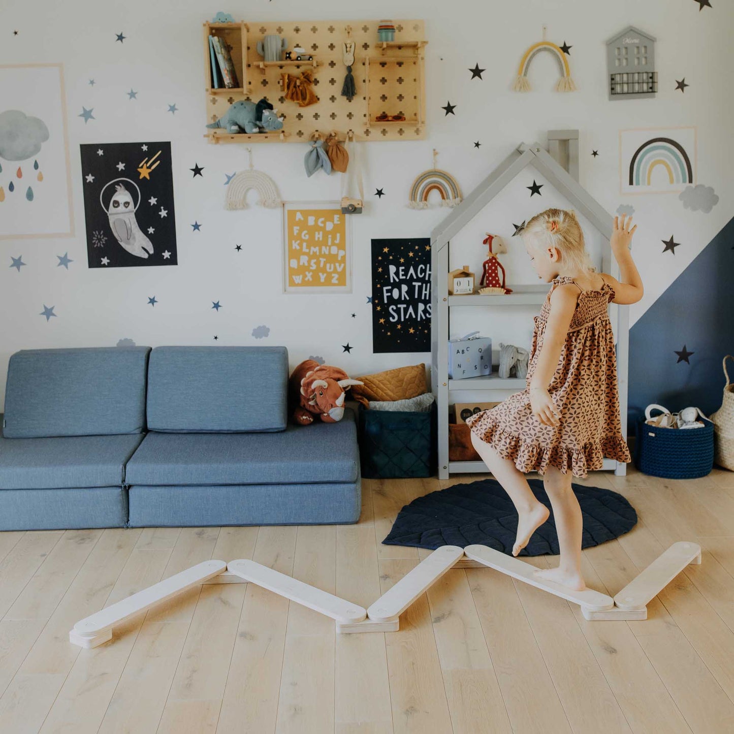 A little girl playing with a Sweet Home From Wood balance beam set in an activity play set in a playroom.