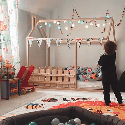 A child's playroom with toys and a Platform house bed with a picket fence.