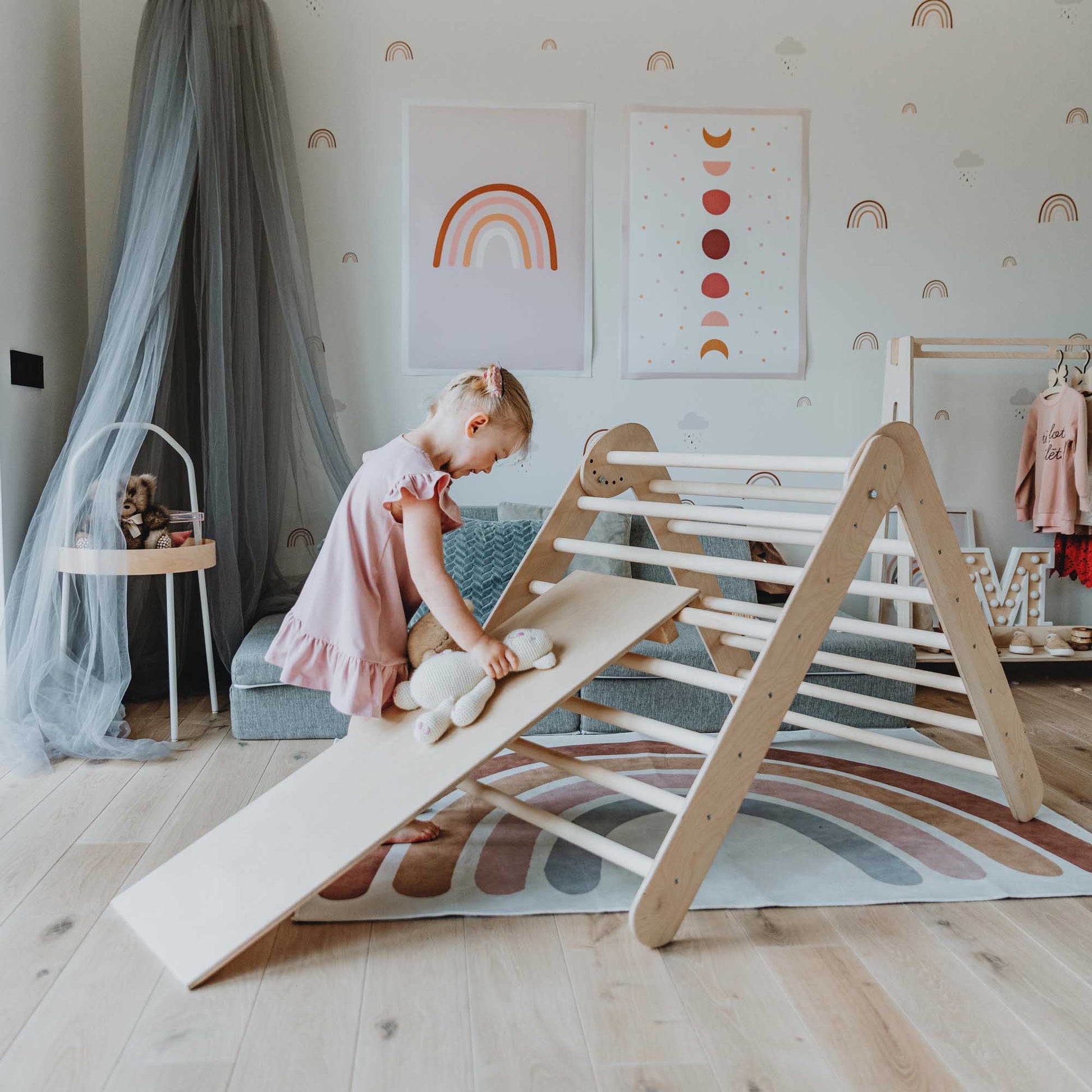 A little girl playing with a Transformable climbing triangle, Foldable climbing triangle, and a ramp in her room, featuring a wooden climber.