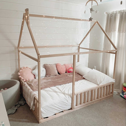 A cozy sleep haven for children with a Sweet Home From Wood Montessori floor house bed with rails made of wood.