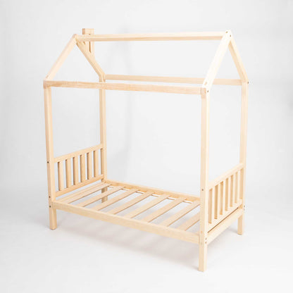 A toddler house bed on legs with a headboard and footboard with a wooden frame and slats.