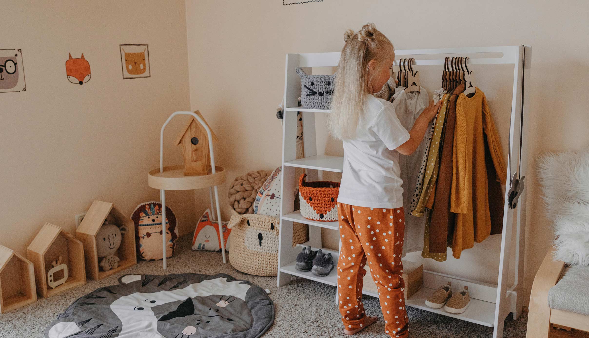 A little girl standing in front of a shelf in a child's room.