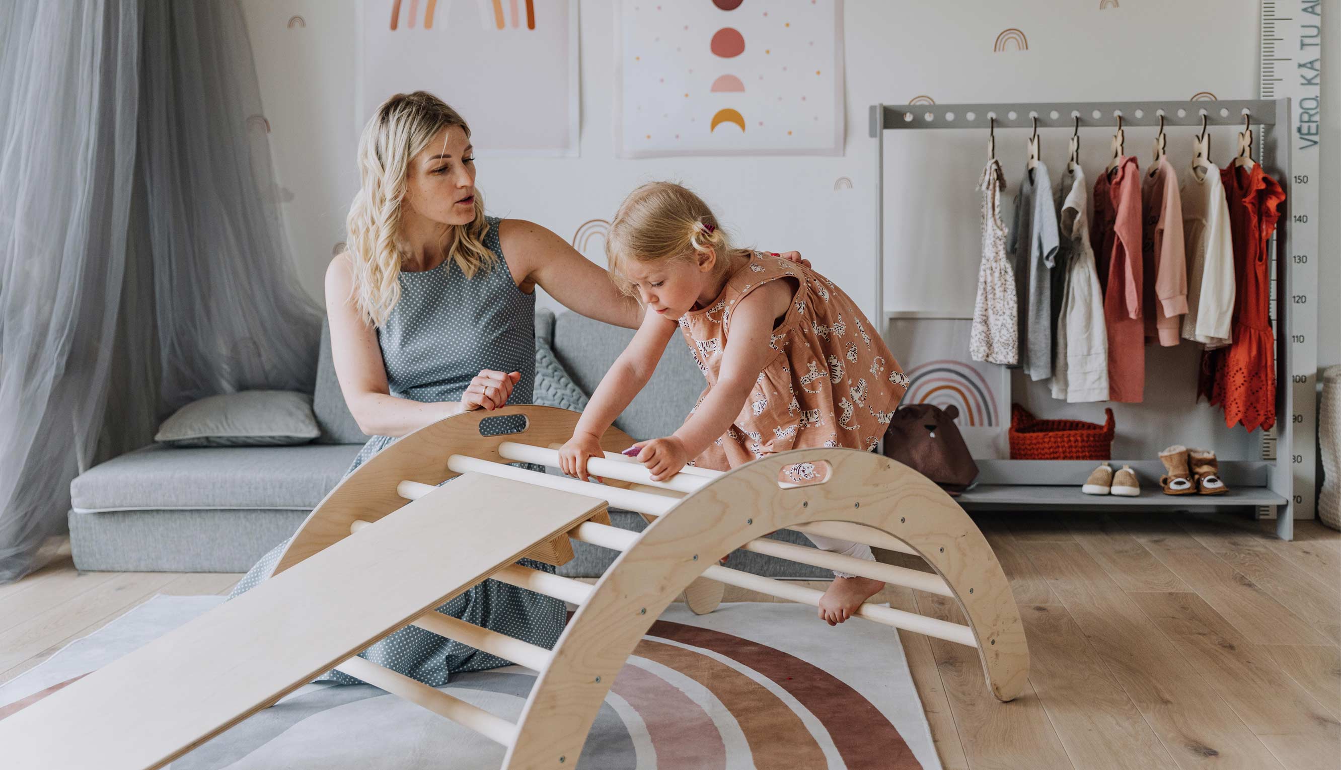 A mother and child playing with a wooden slide in a room.