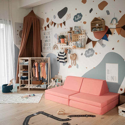 A children's room with an Activity Play Couch Set, wall decorations, a clothing rack, toys, and a rug. The space also features a charming play tent for imaginative adventures. The walls are painted with abstracts and adorned with various items like an alphabet chart, bunting, and "hello" signs.