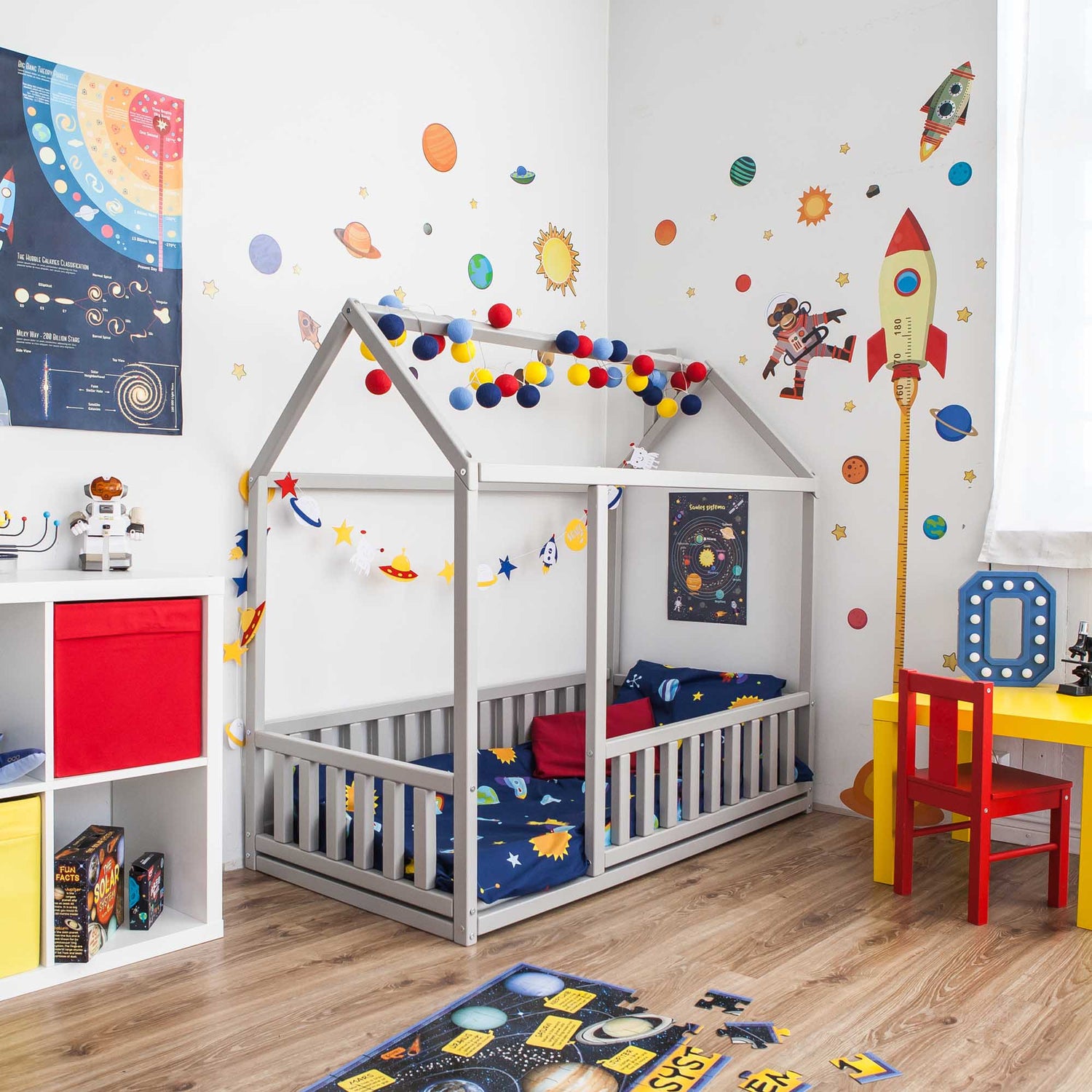 A cozy sleep haven for children with a space theme featuring a Sweet Home From Wood Montessori floor house bed with rails.