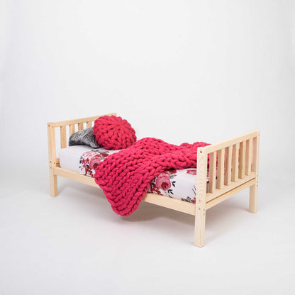 A 2-in-1 kid's bed on legs made of solid pine or birch wood with a pink blanket.