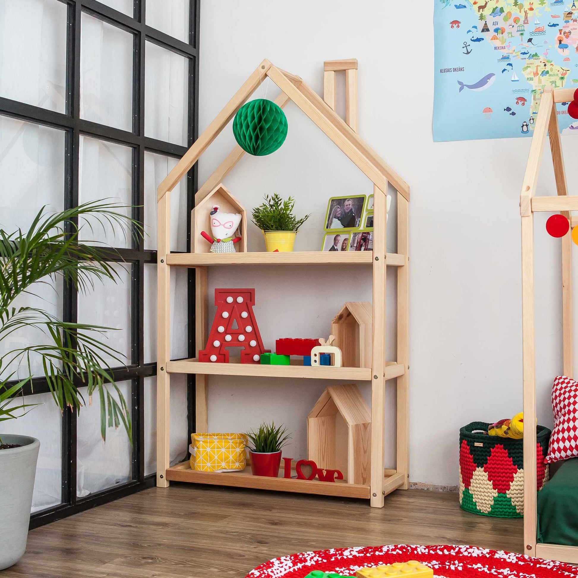 A children's room with an open House-shaped Montessori shelf and Sweet Home From Wood toys.