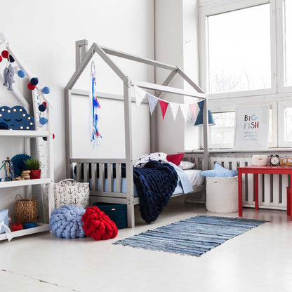 A child's room with a toddler house bed on legs with a headboard and footboard, toys, and a rug.