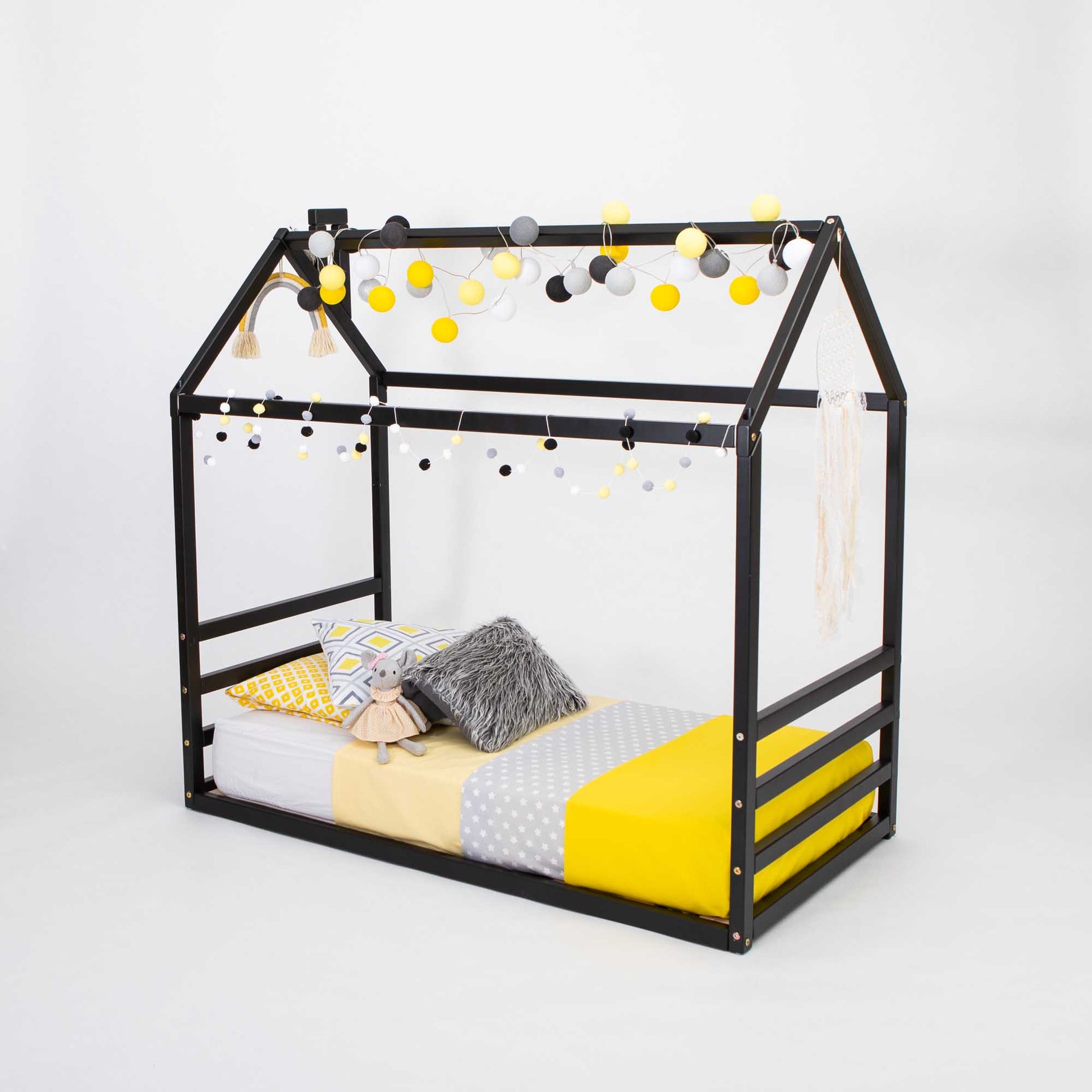 A Floor house-frame bed with a horizontal headboard and footboard adorned with yellow pom poms.