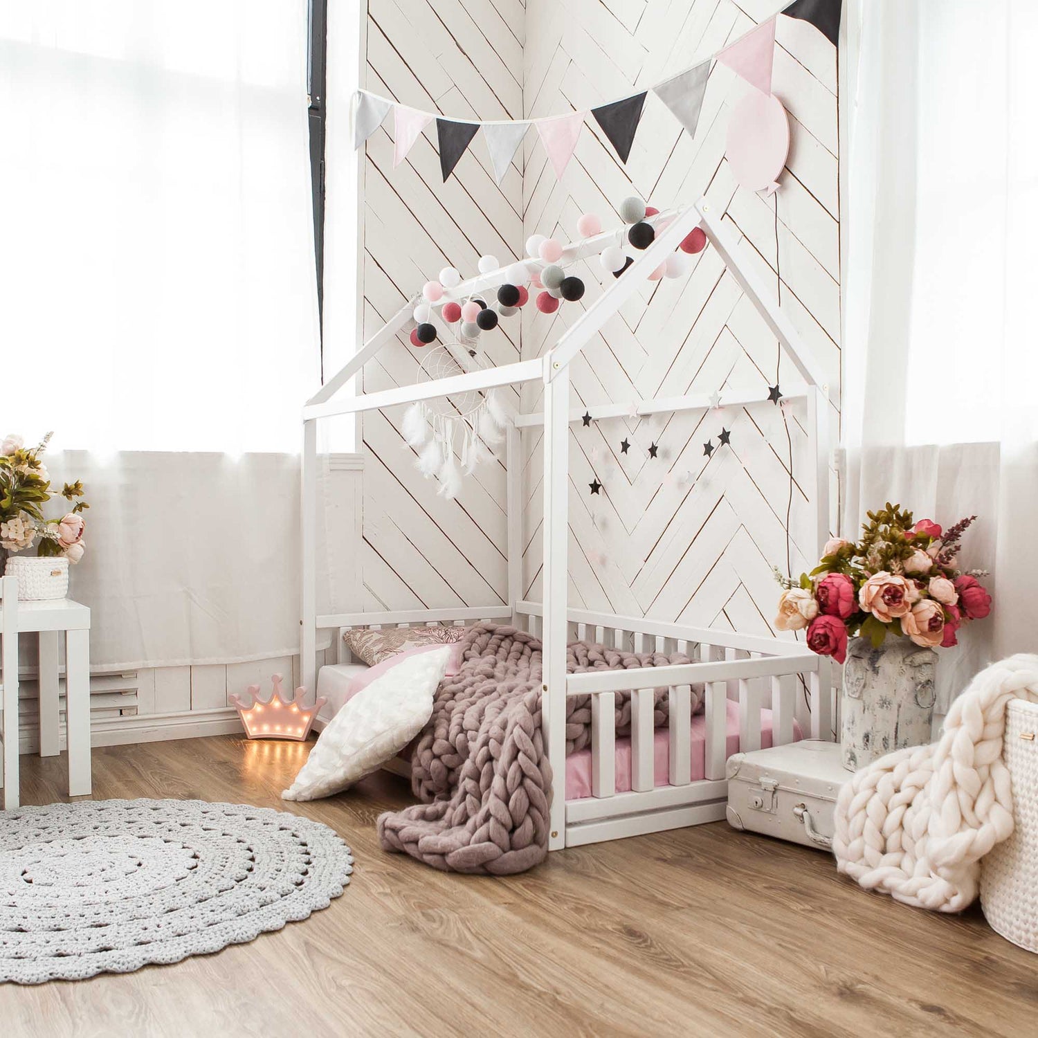 A cozy sleep haven for a preschool girl, featuring a Sweet Home From Wood Kids' house-frame bed with 3-sided rails adorned with pink and white decorations.