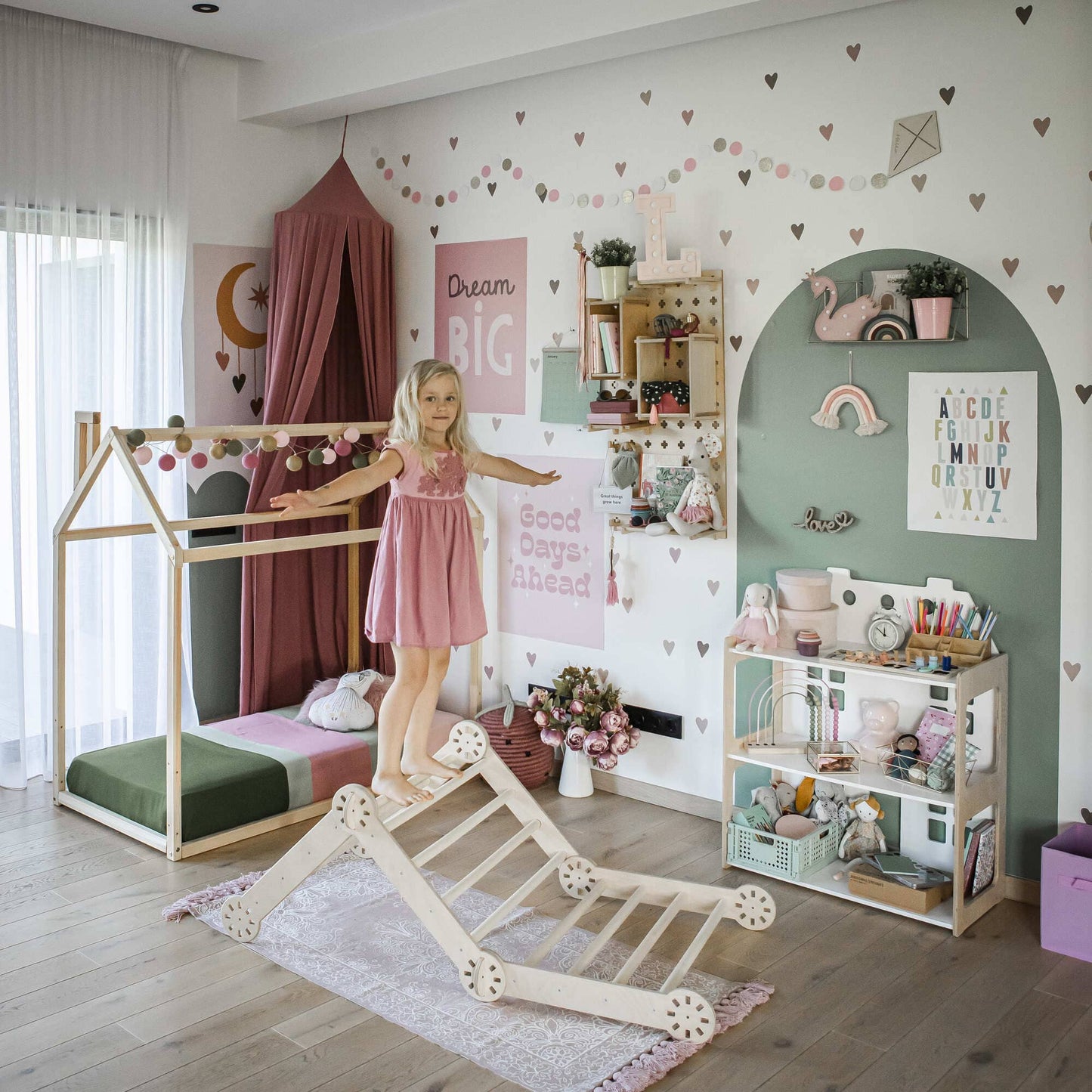 A young girl balances on an indoor toy—the Transformable climbing gym—in a decorated children's room with a bed, bookshelf, and themed wall decorations.