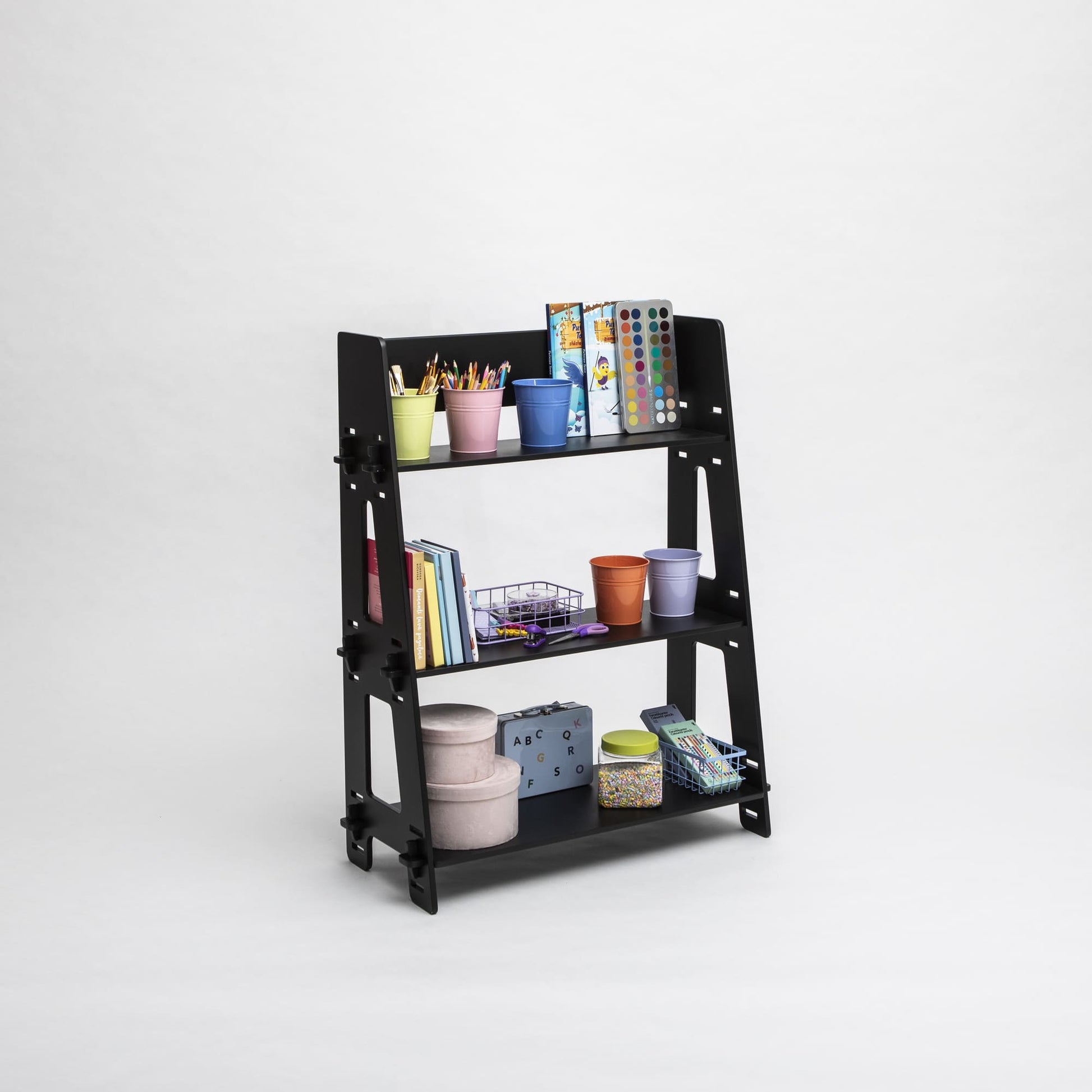 A black three-tiered Montessori toy shelf filled with art supplies, books, and storage boxes against a plain white background, perfect for nursery organization.