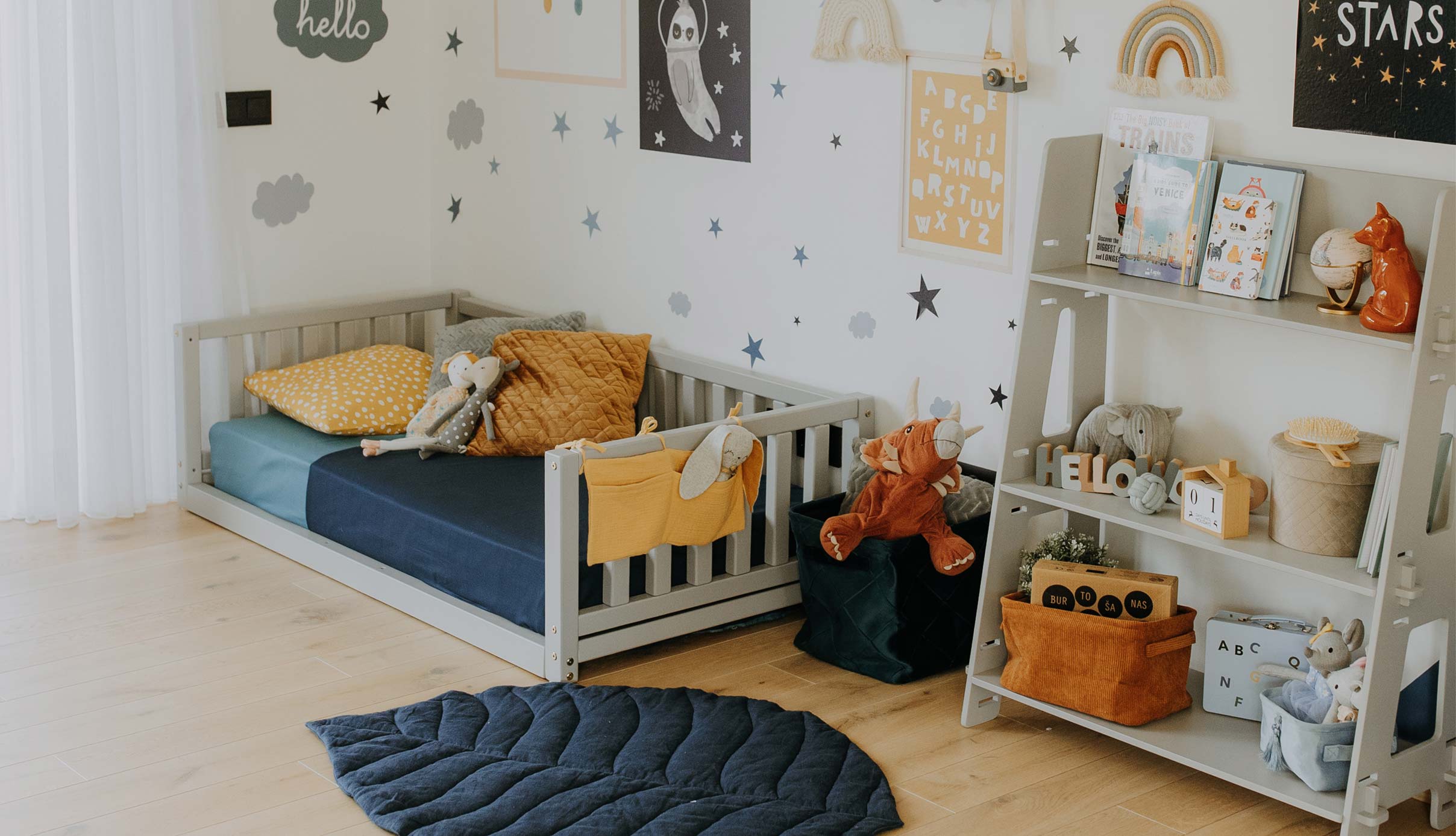 A child's room with a bed, bookshelf, and wall art.