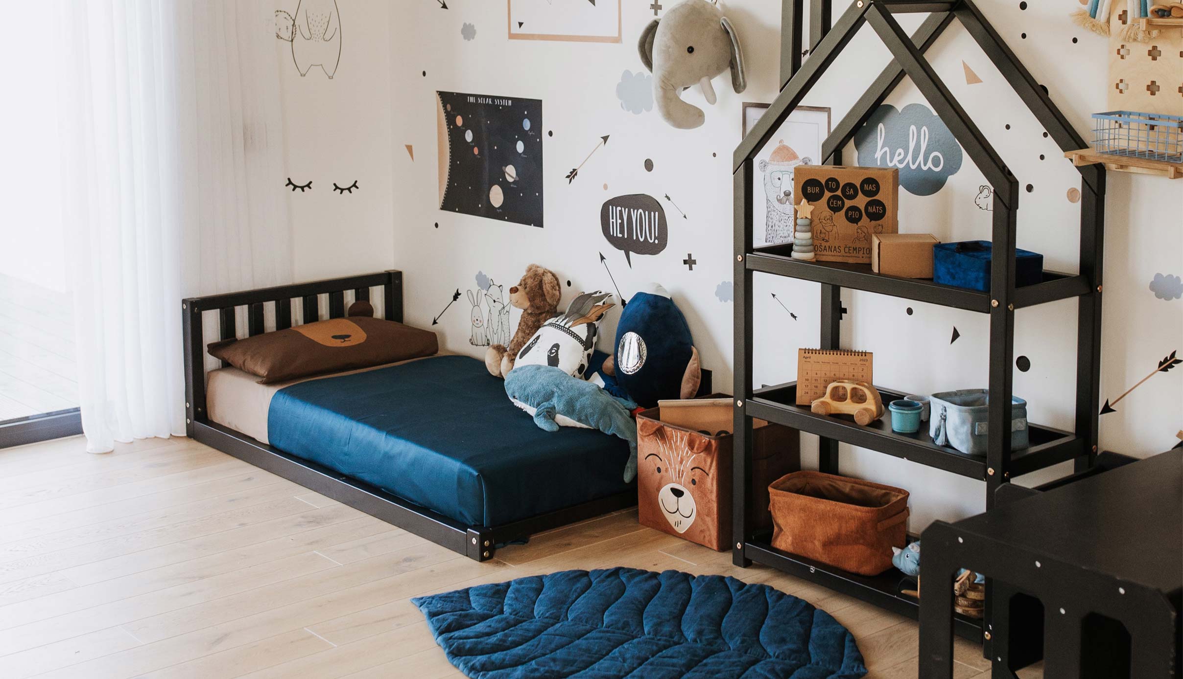A boy's room with a bed, bookshelf, and a teddy bear.