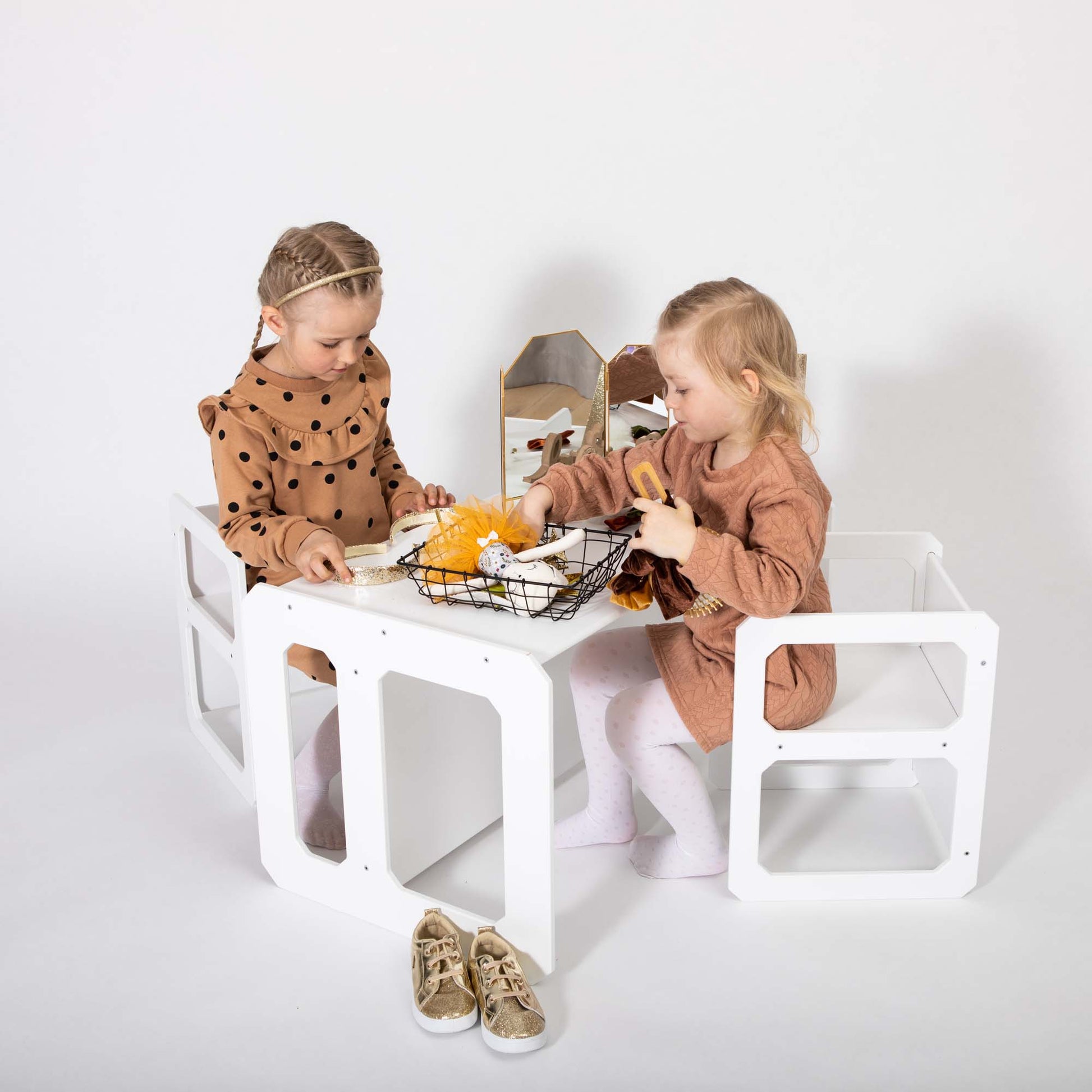 Two young children are sitting in a Montessori weaning table and 2 chair set, playing with stuffed animals and toys on the white surface, fostering independence and encouraging fine motor skill development.
