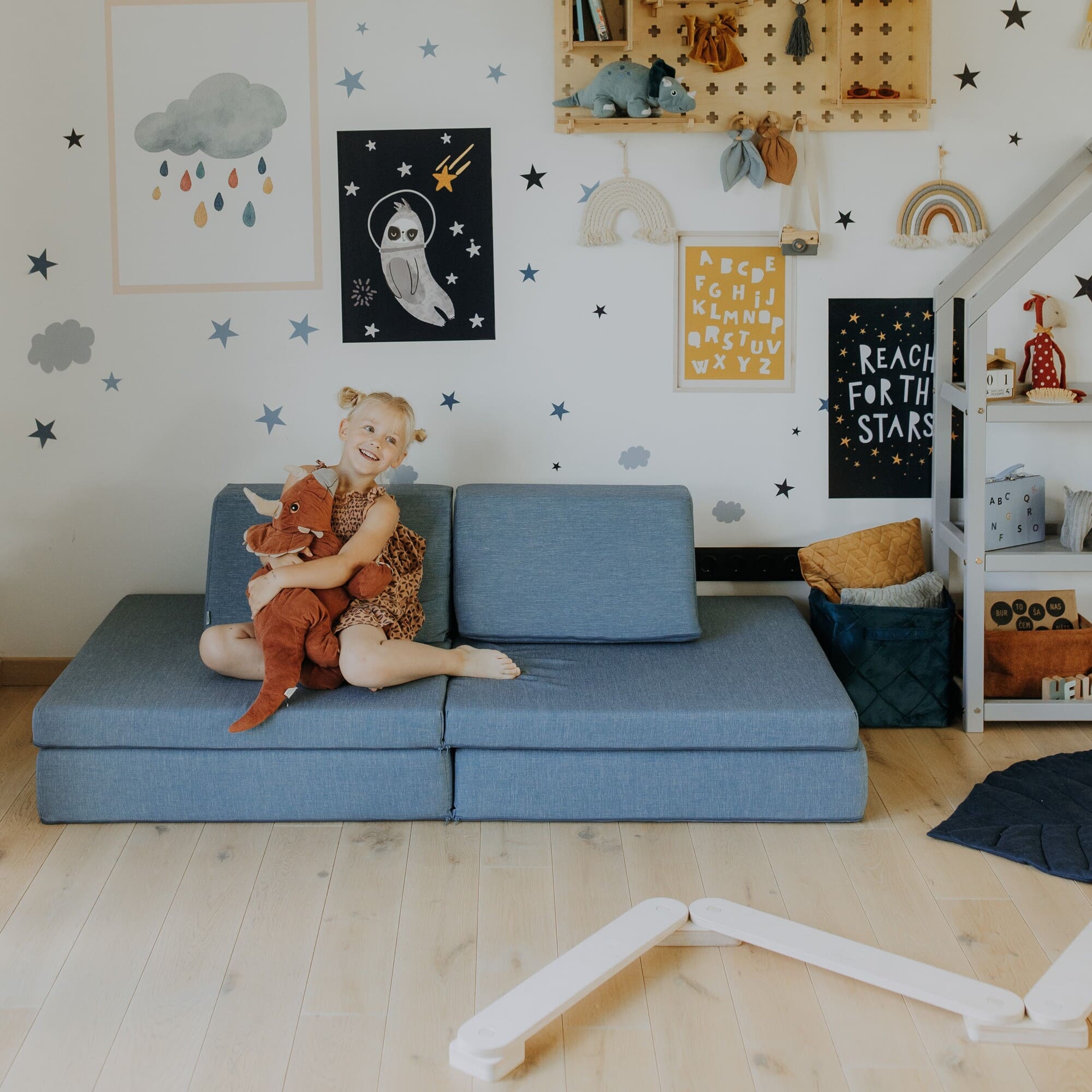 A girl sitting on her turquoise kids play couch.