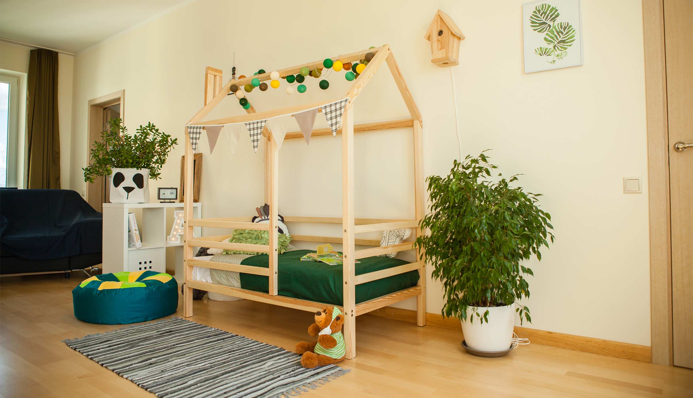 A child's room with a wooden bed and green plants.