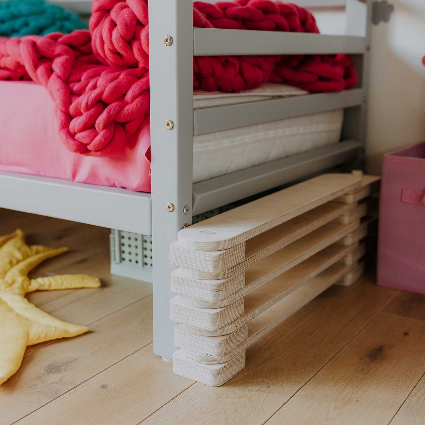 A Balance beam set from Sweet Home From Wood with a pink blanket under it.