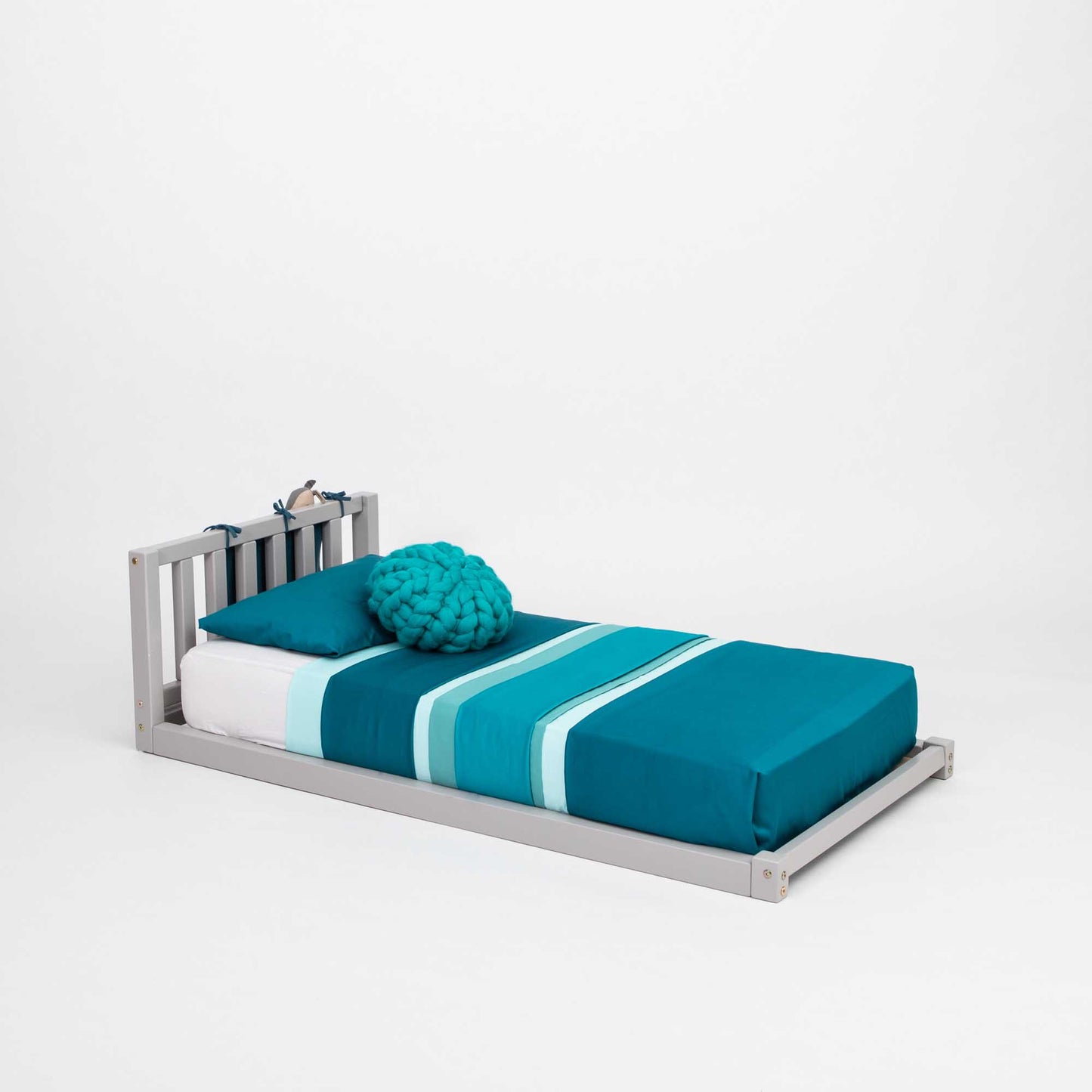 A Montessori-inspired toddler bed with blue and teal bedding.