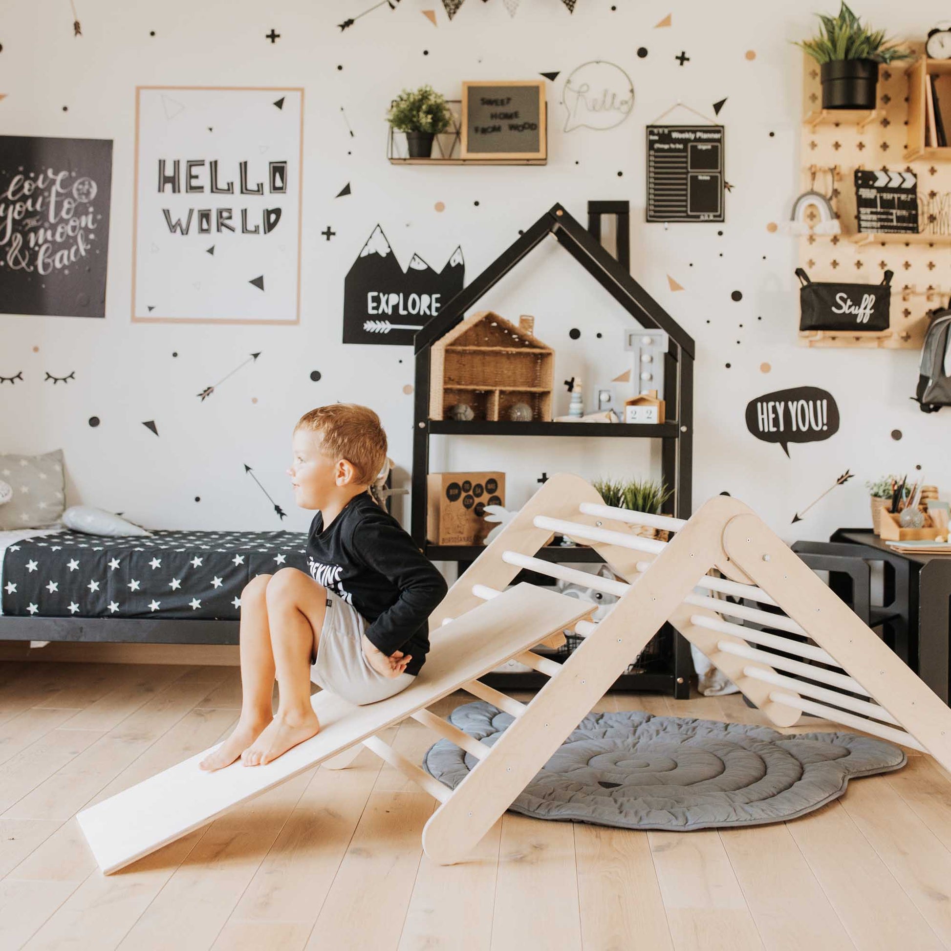 A baby sitting on a Climbing triangle + Foldable climbing triangle + a ramp in his eco-friendly room.