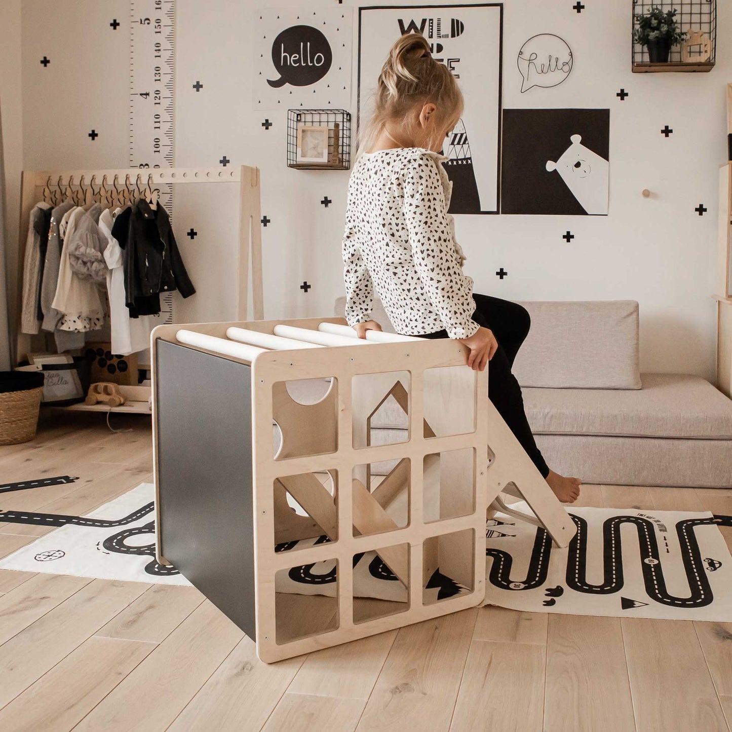 A little girl sitting on a Transformable climbing cube / table and chair in a child room.