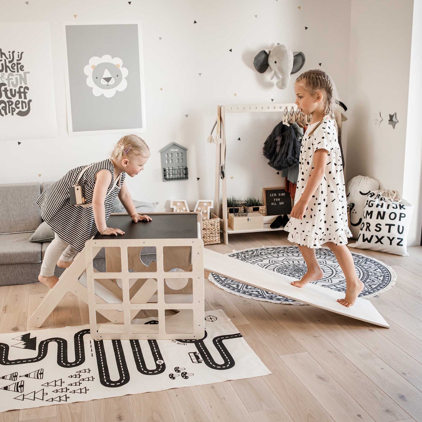 Two girls playing on a transformable climbing cube / table and chair + ramp in a playroom.