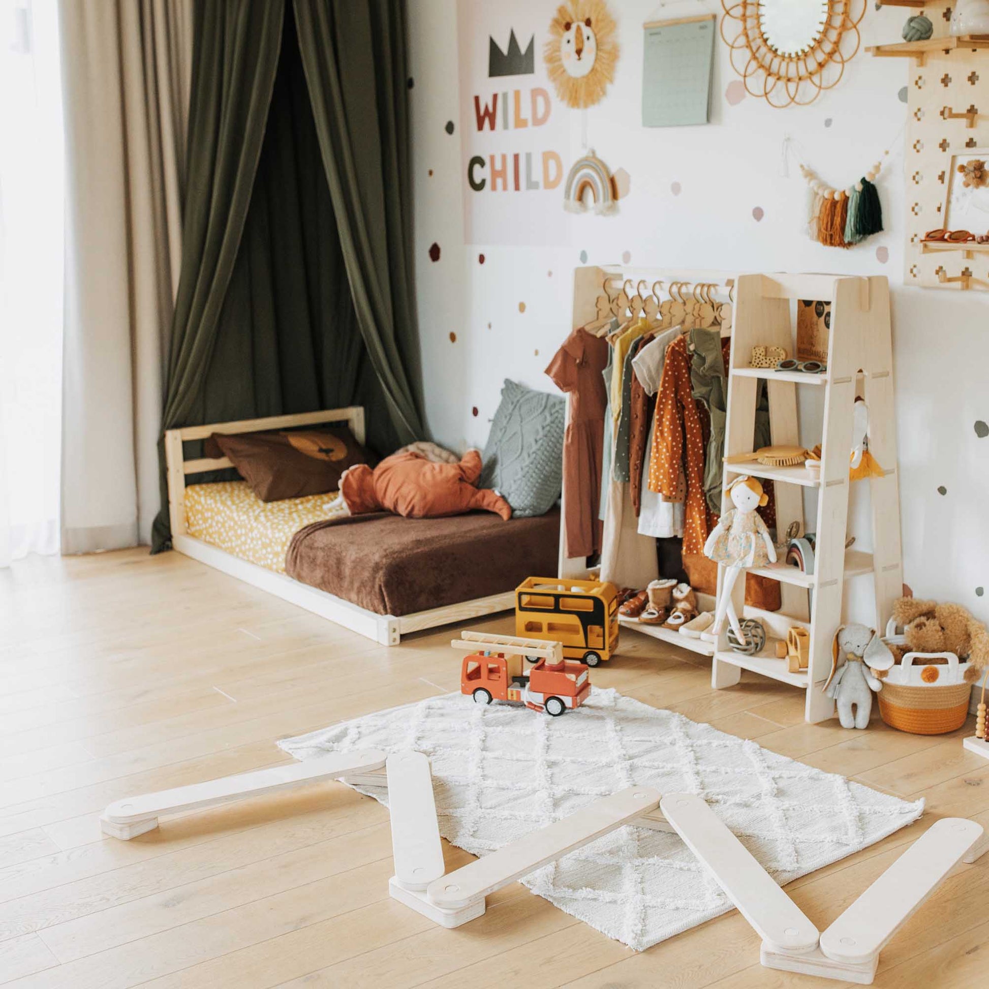 A child's room with toys, a 2-in-1 transformable kids' bed with a horizontal rail headboard, and a montessori bed from Sweet Home From Wood.