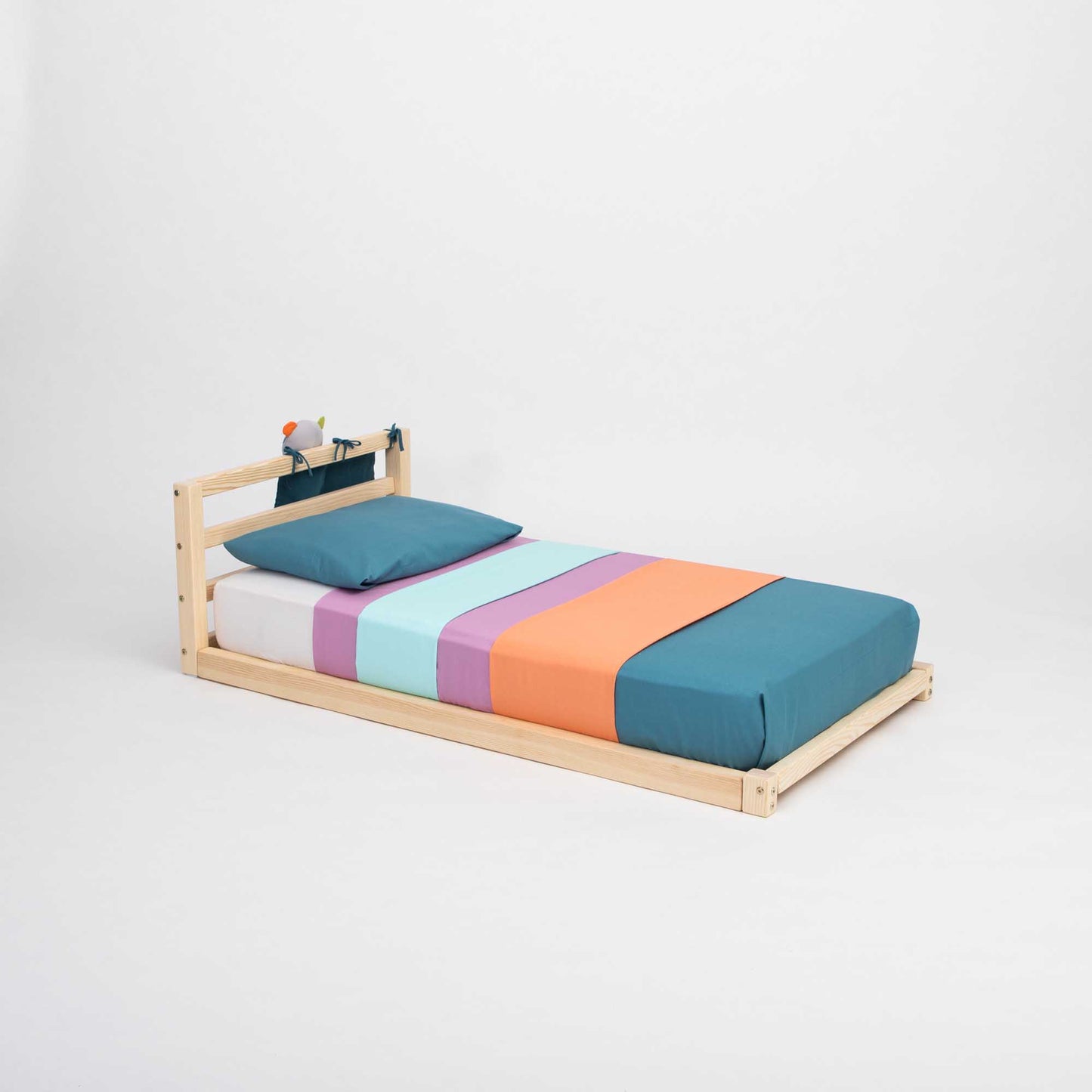 A 2-in-1 transformable kids' bed with a horizontal rail headboard for children with a wooden frame and colorful sheets that grows with the child from Sweet Home From Wood.