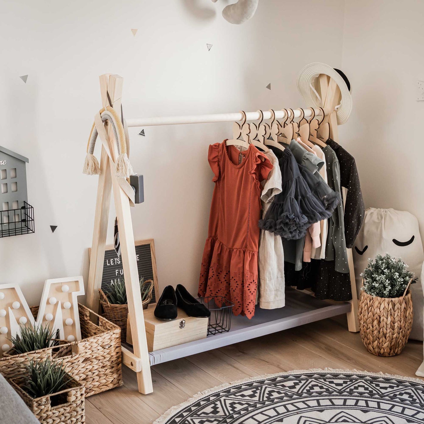 A Montessori-inspired child's room with clothes hanging on a Sweet Home From Wood Kids' clothing rack with storage.