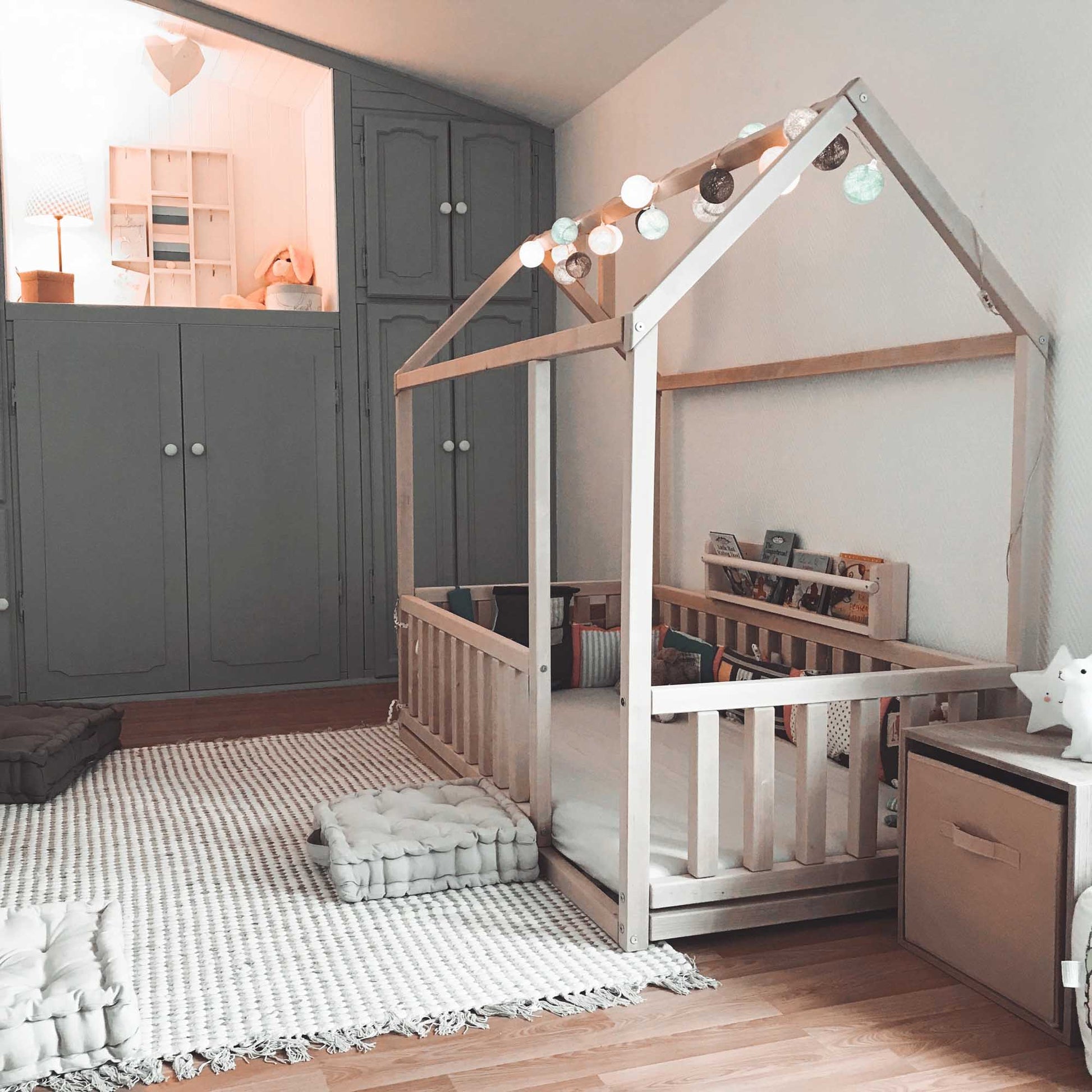 A cozy sleep haven with a Sweet Home From Wood Montessori floor house bed with rails accompanied by a bed frame.