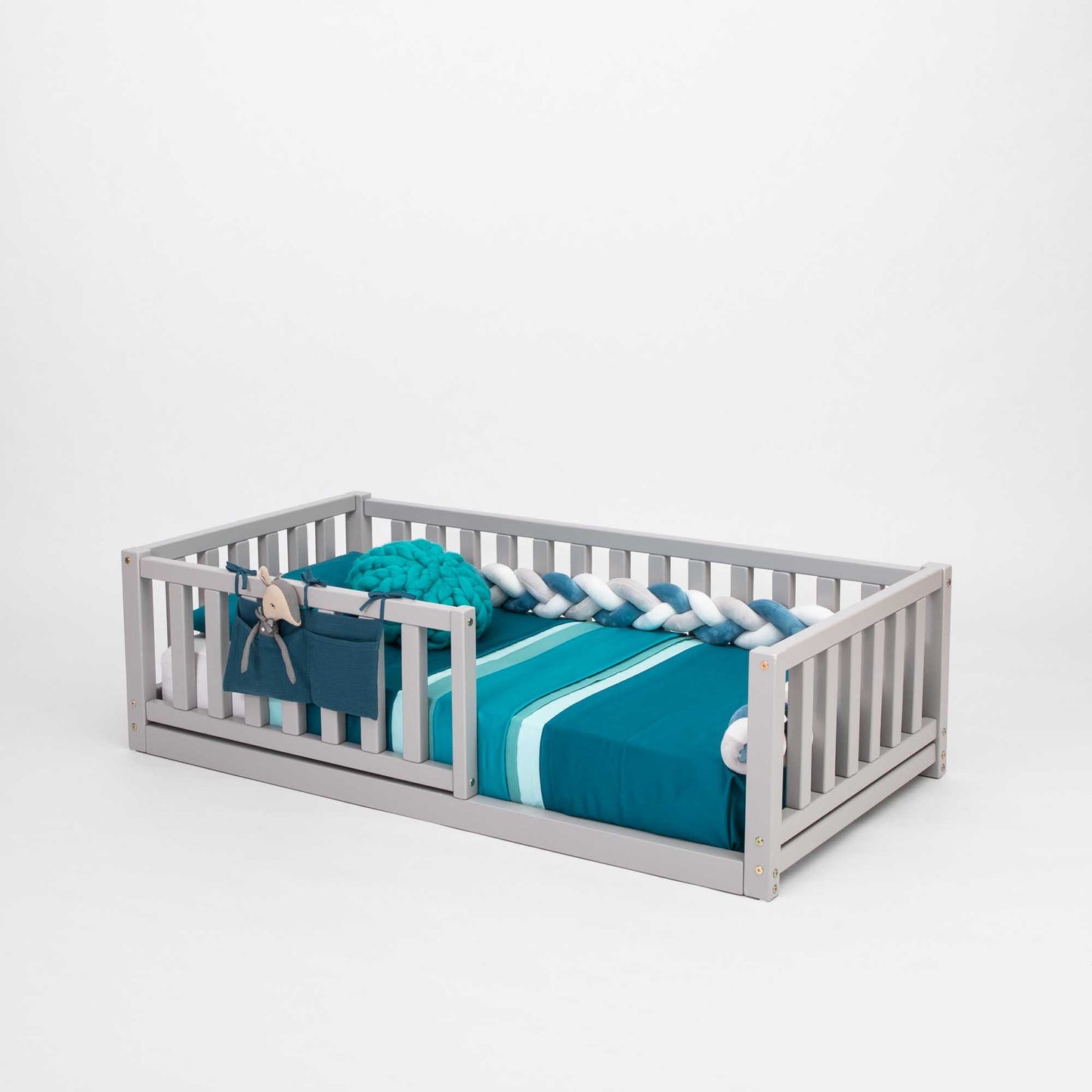 A Montessori kids' bed with a fence and blue and white bedding designed for independent sleeping by Sweet Home From Wood.