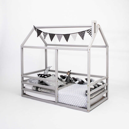 A floor level house bed with a horizontal fence with bunting.