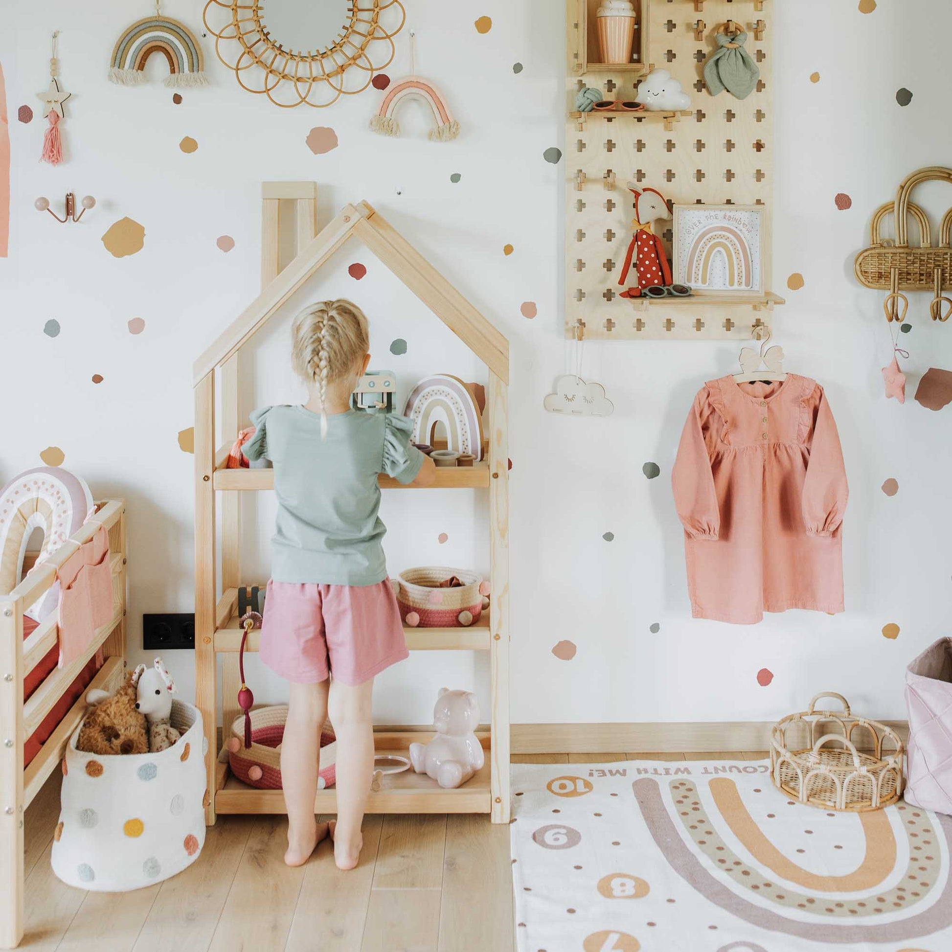 A child's room with polka dot wall art and a wooden bed featuring a Sweet Home From Wood house-shaped Montessori toy shelf.