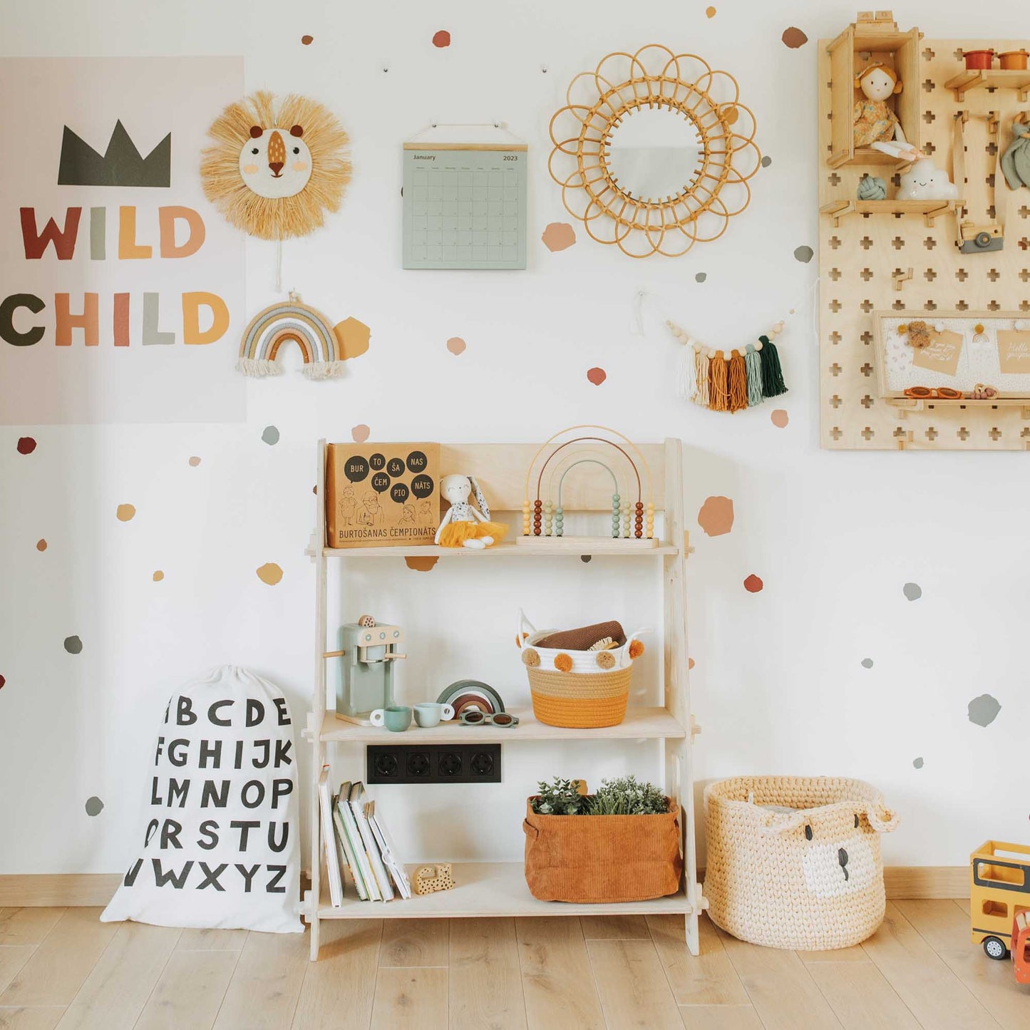 A toddler's room with a lot of Montessori toy shelves from Sweet Home From Wood and a polka dot wall.