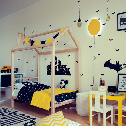 A boy's room featuring a unique Kids' house bed on legs with a headboard decorated with bats and yellow accents.