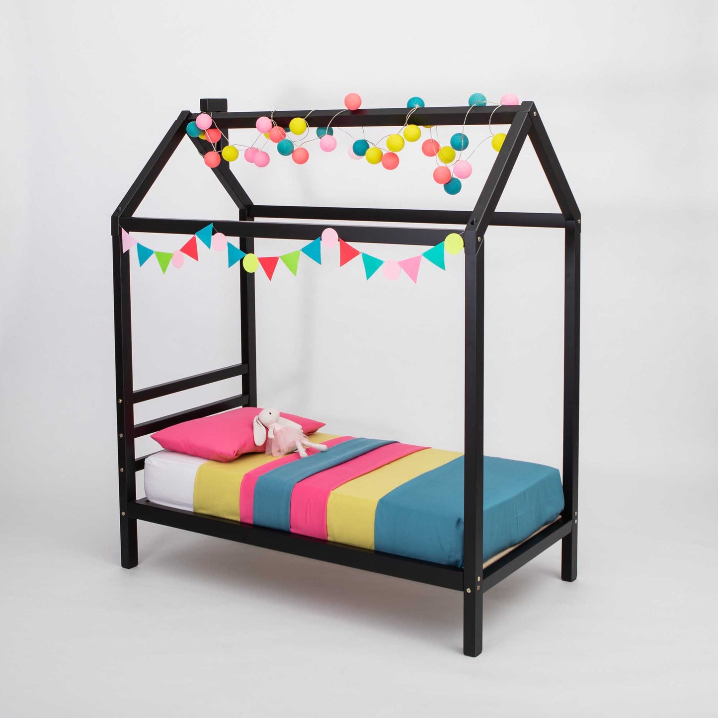 A Kids' house bed on legs with a headboard, with a black frame and colorful bedding, raised on legs like a house bed.
