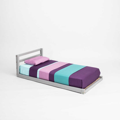 A 2-in-1 transformable kids' bed with a horizontal rail headboard from Sweet Home From Wood, with a purple, blue, and green striped sheet that can grow with your child.