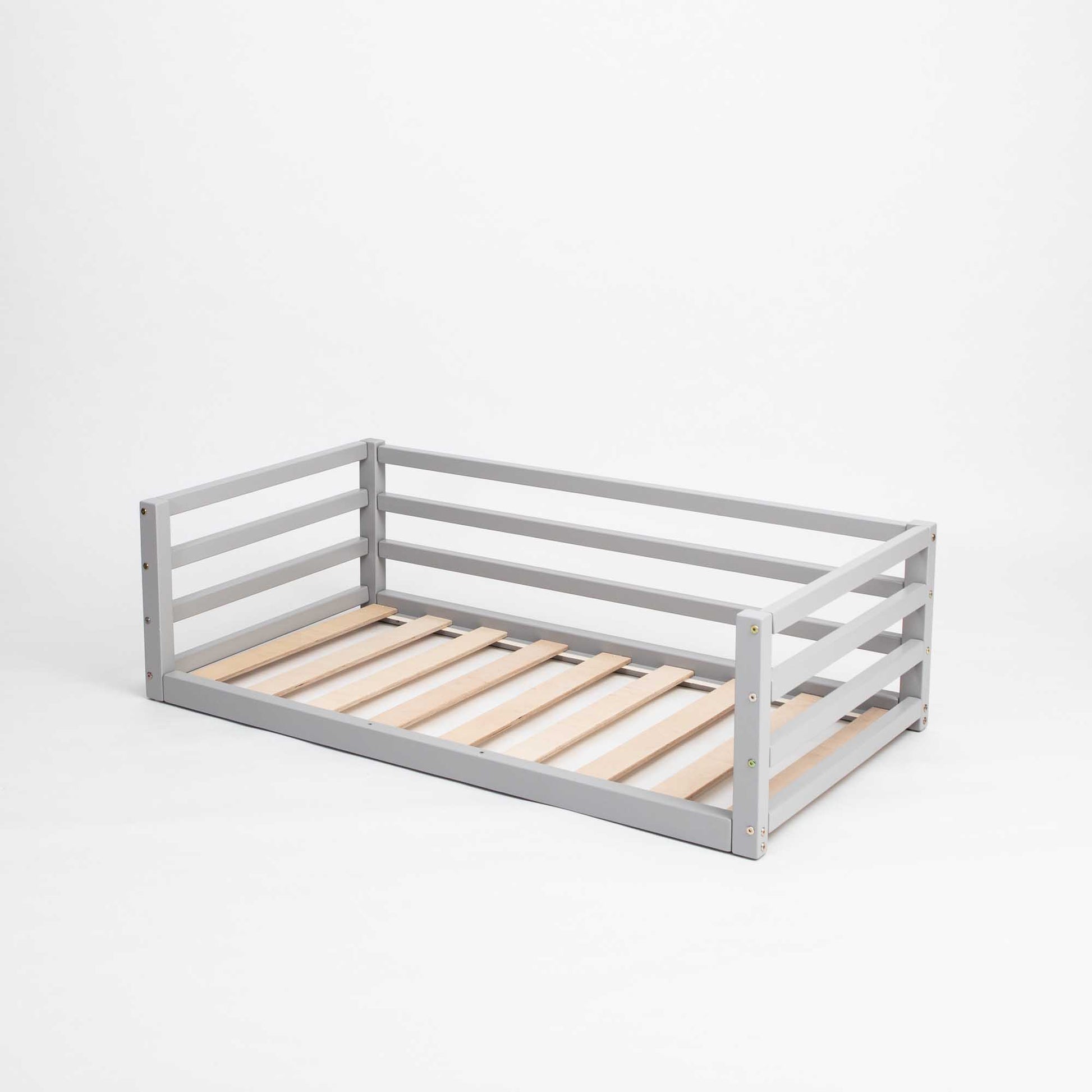 A grey wooden Sweet Home From Wood transitional toddler bed with wooden slats and a Children's floor level bed with 3-sided safety rail for children.